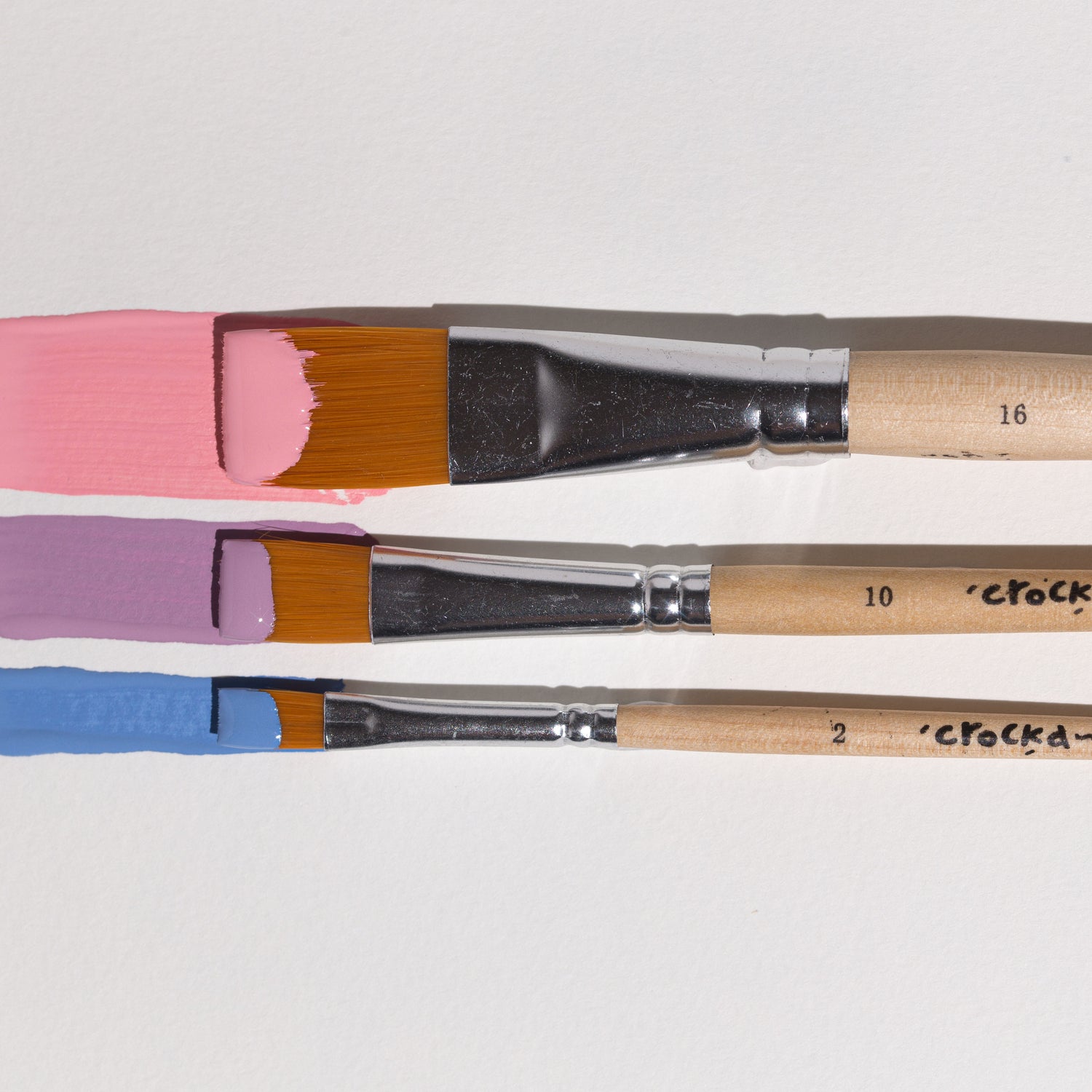 Crockd paint brushes with paint on them lying against each other
